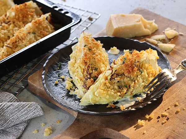Gebackene Spitzkohlviertel mit Parmesan-Kräuter-Kruste auf einem Backblech
