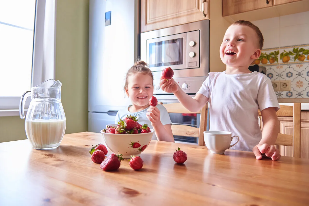Rodzic z dzieckiem i truskawkami, zaniepokojony, ale spokojny wyraz twarzy
