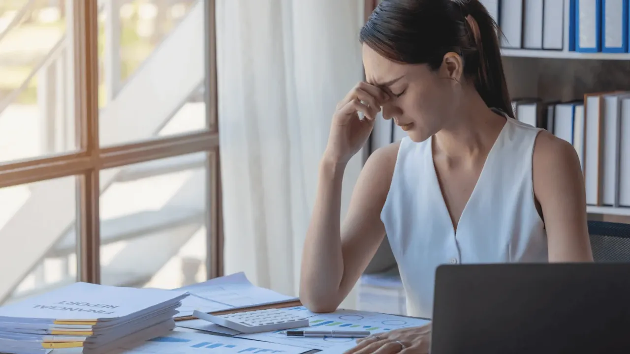 Zmęczona kobieta przy biurku, zmagająca się z wypaleniem zawodowym. Kto wystawia L4 w takiej sytuacji? Lekarz.