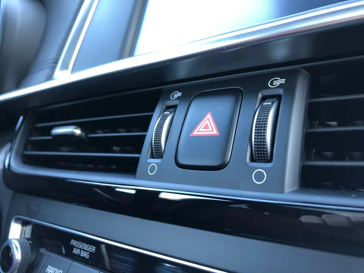 Przycisk świateł awaryjnych w samochodzie, otoczony nawiewami. Widać jeden czerwony trójkąt, który informuje, ile jest świateł awaryjnych.