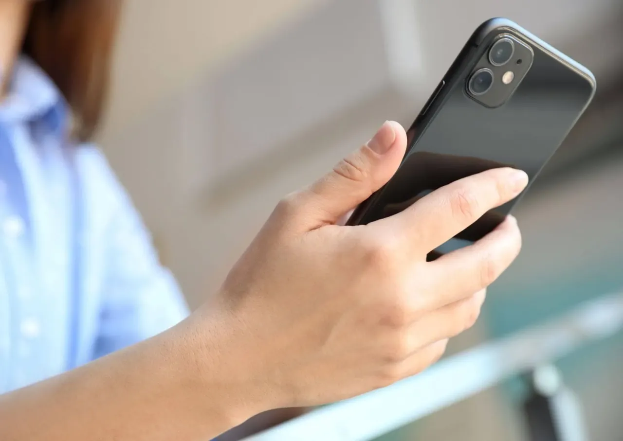 Dłoń trzyma czarny iPhone 11. Zastanawiasz się, ile kosztuje wymiana baterii w iPhone 11?