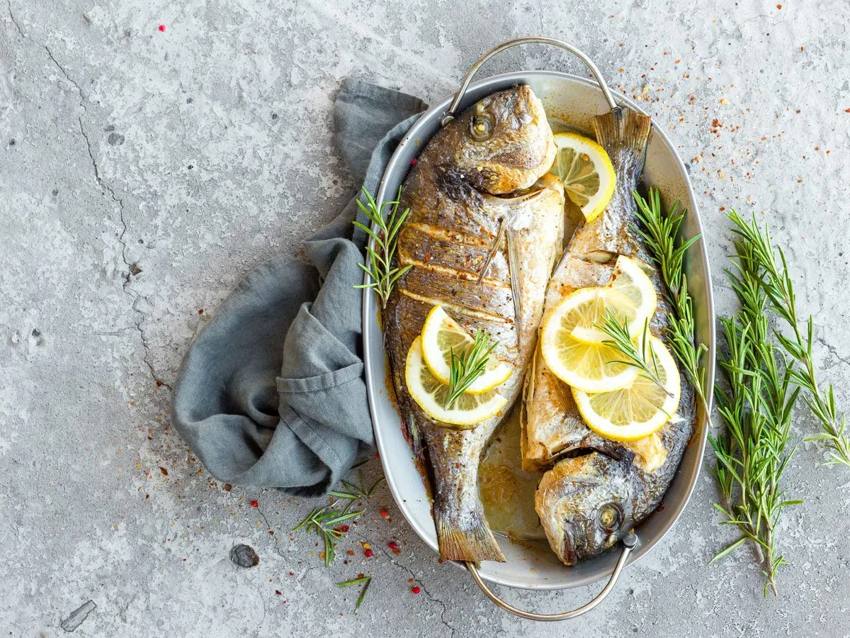 Dwa pieczone dorady z cytryną i rozmarynem. Idealne jakie przyprawy do ryby na obiad.