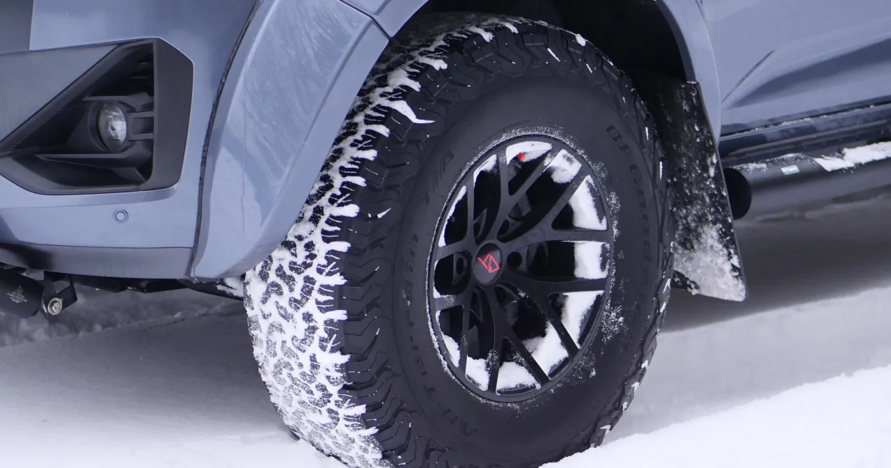 Koło samochodu terenowego w śniegu, z widocznym bieżnikiem i felgą.