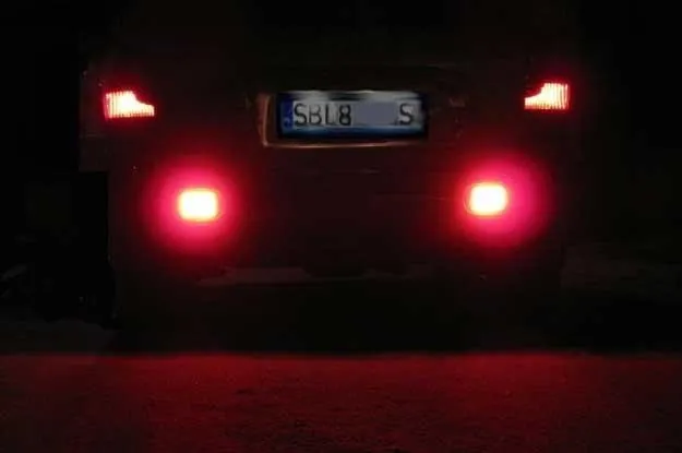 samochód z włączonymi tylnymi światłami przeciwmgłowymi w gęstej mgle