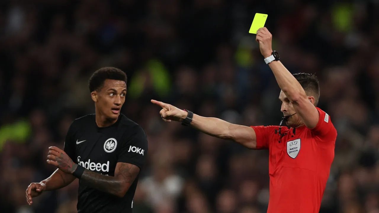 sędzia pokazuje ż&oacute;łtą kartkę piłkarzowi