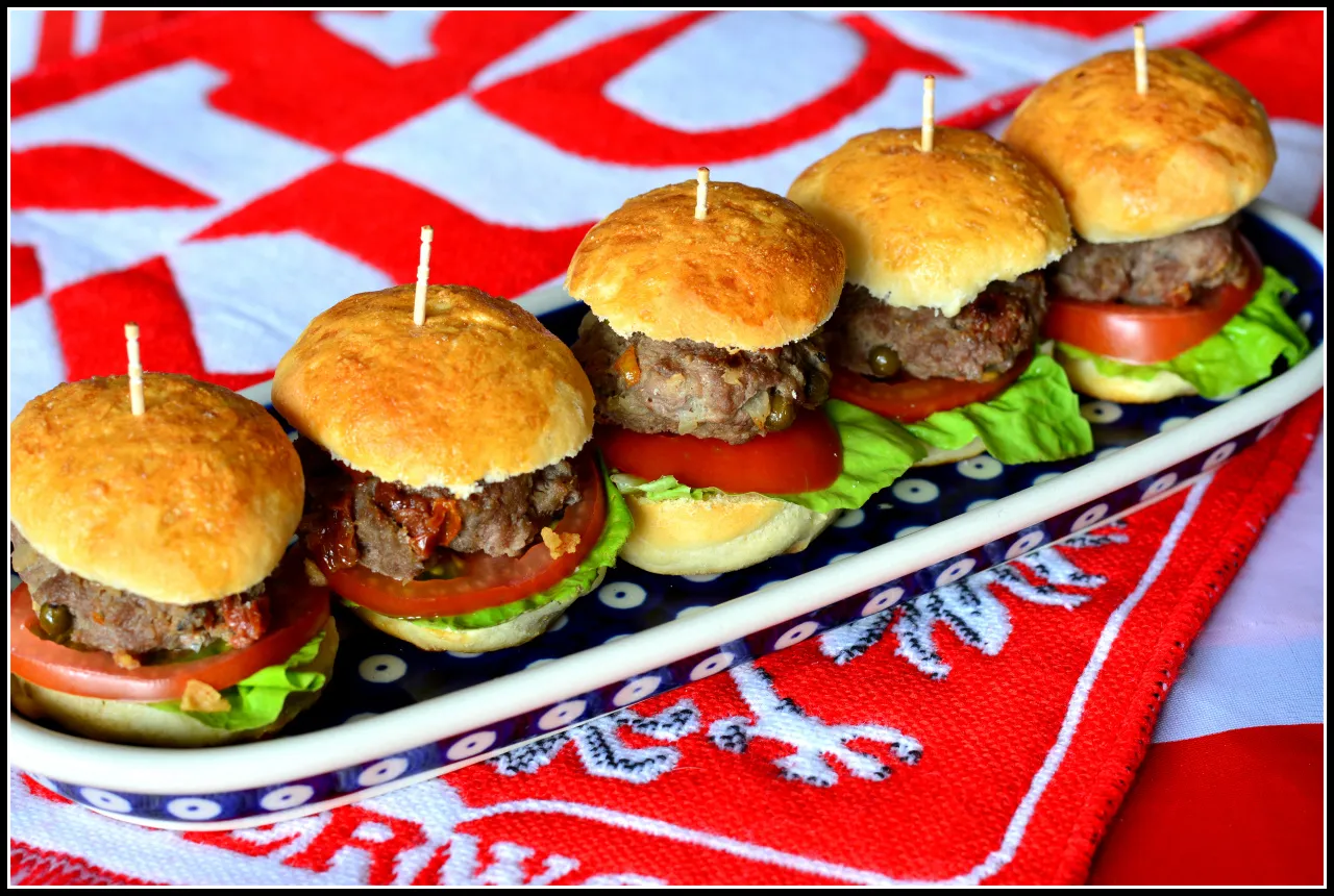 Mini bułeczki do burgerów z kotletem, pomidorem i sałatą na talerzu. Gdzie kupić takie pyszności?