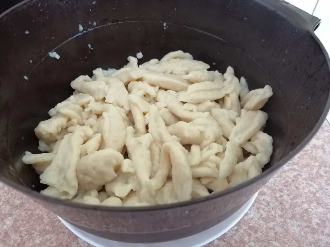 Osoba kładąca kluski łyżką do wrzątku