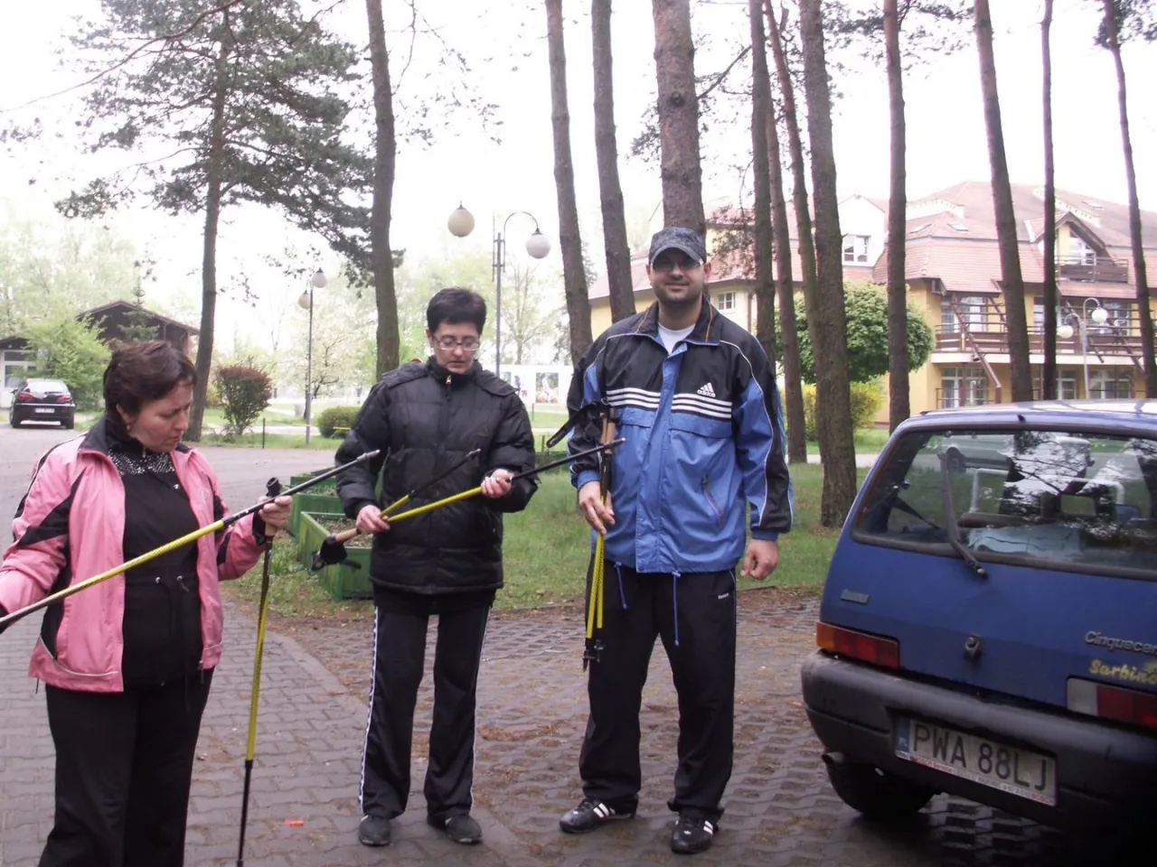 Narciarz z kijkami pokazujący prawidłową postawę i kąt ramienia