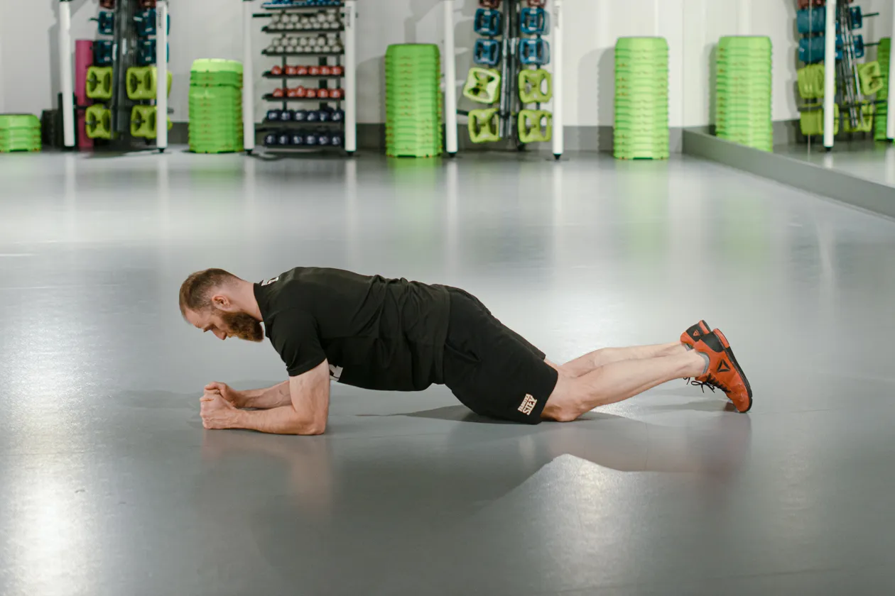 Mężczyzna wykonuje ćwiczenie deska. Ile razy dziennie? To zależy od Twojej kondycji, ale regularność jest kluczem do sukcesu.