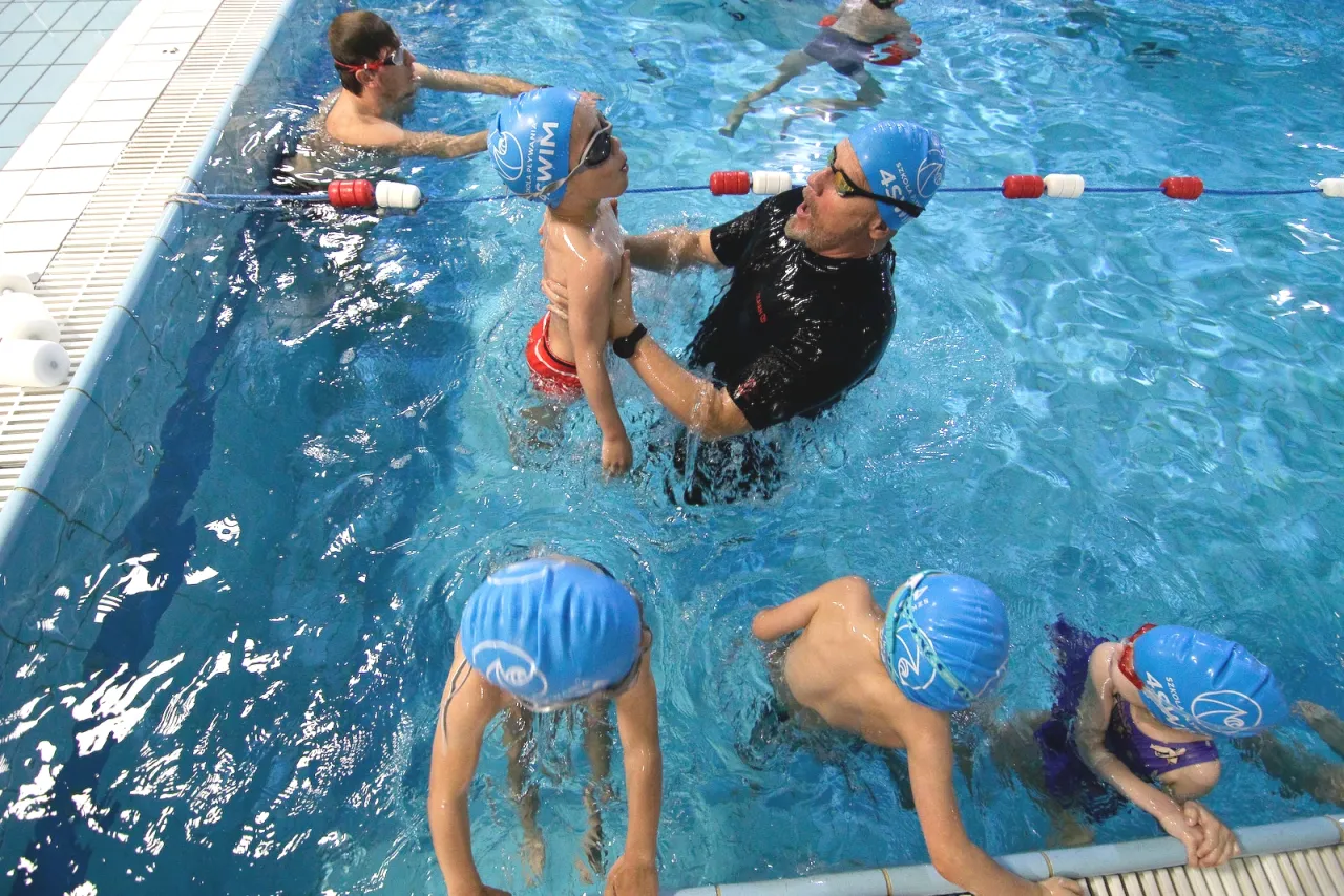 Instruktor uczy chłopca pływać. Dowiedz się, ile kosztuje indywidualna lekcja pływania, by Twoje dziecko też mogło czerpać radość z wody.