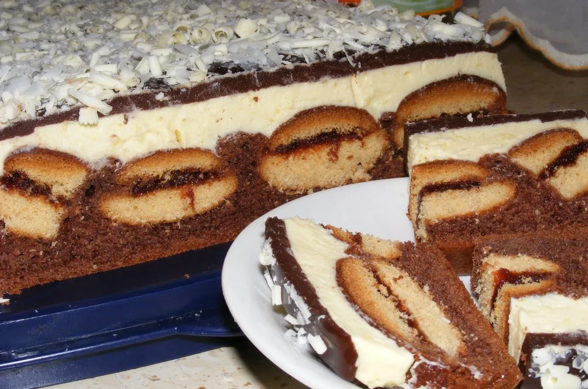 Przepis na ciasto usta romana: czekoladowy biszkopt, kremowa masa, biszkopty z dżemem i wiórki białej czekolady.