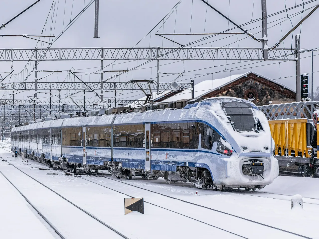 Pociąg PKP Intercity pokryty śniegiem na mroźnej stacji. Zastanawiasz się, ile kosztuje bilet TLK na podr&oacute;ż w takich warunkach?