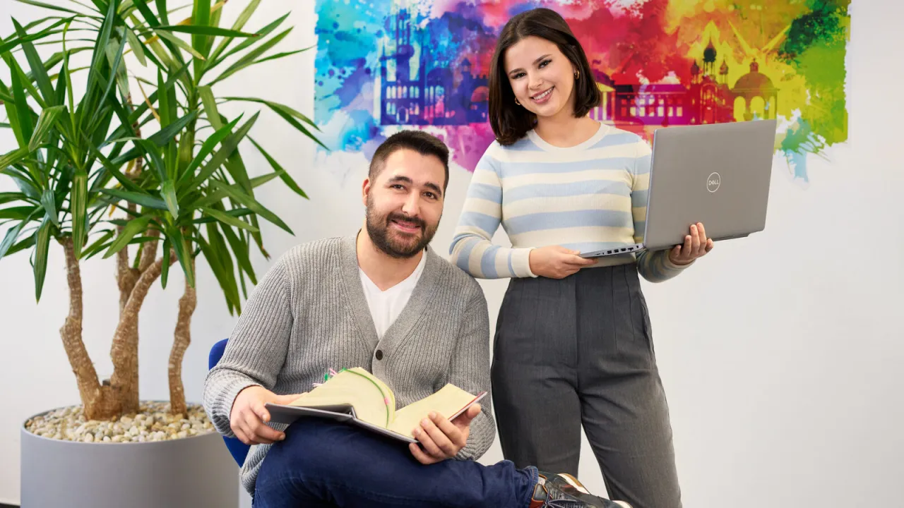 Młoda osoba na stażu w biurze, uśmiechnięta, z laptopem