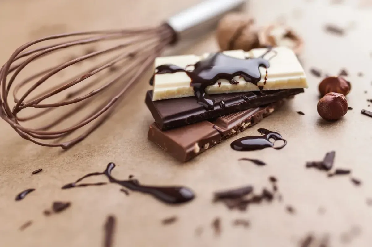 Stos czekolady, rózga i orzechy laskowe. Zastanawiasz się, dlaczego polewa czekoladowa się rozwarstwia?