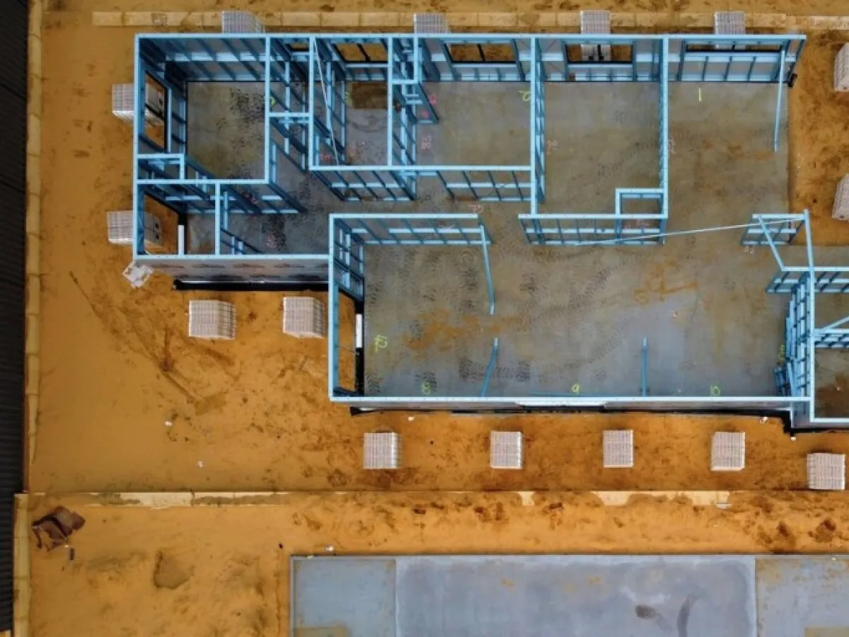 Szkielet domu z profili stalowych na placu budowy. Widać, jak głęboko fundamenty są przygotowane pod budowę.