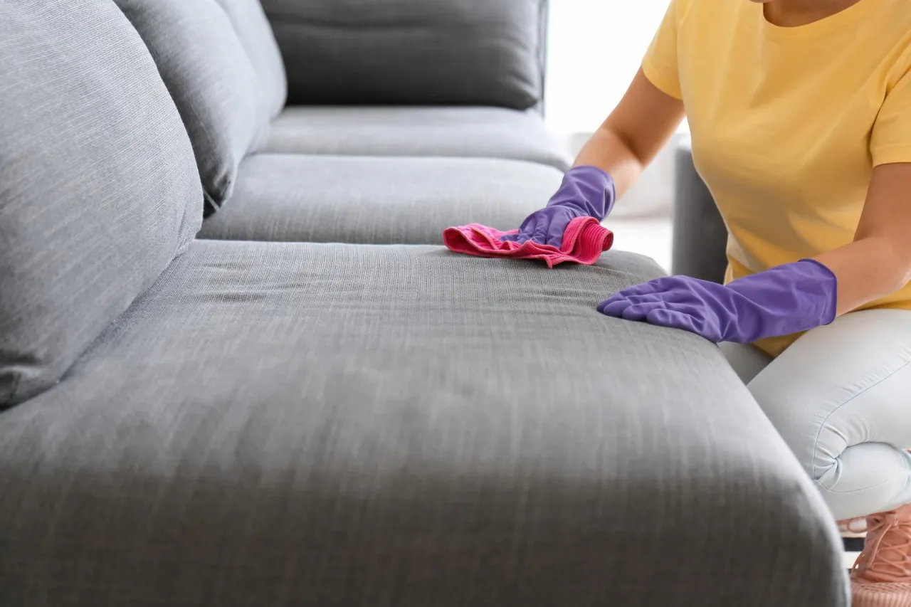 osoba odsączająca plamę z kanapy ręcznikiem papierowym