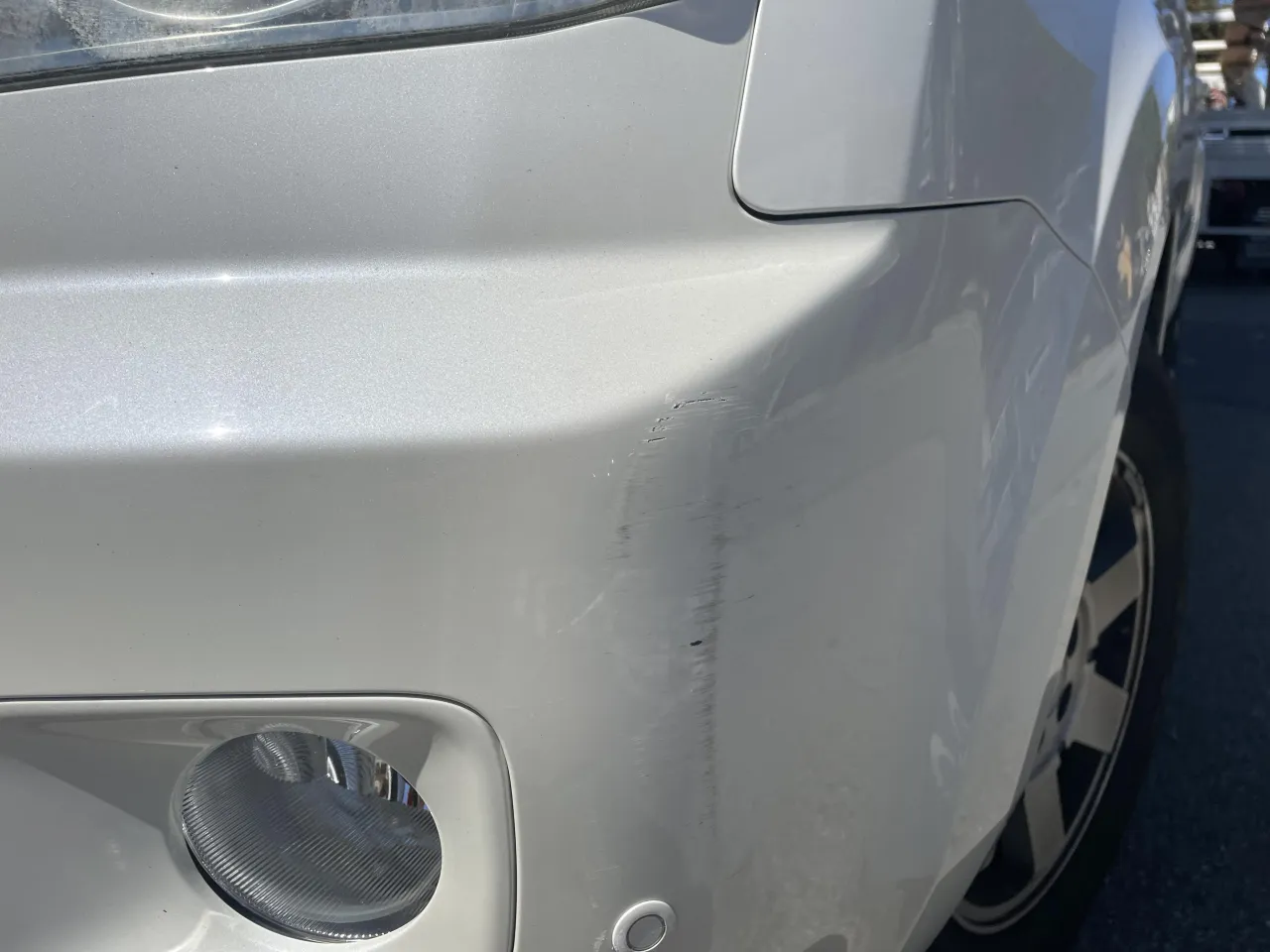 Zderzak w kolorze z widocznymi zarysowaniami, w przeciwieństwie do gładkiego zderzaka do malowania.