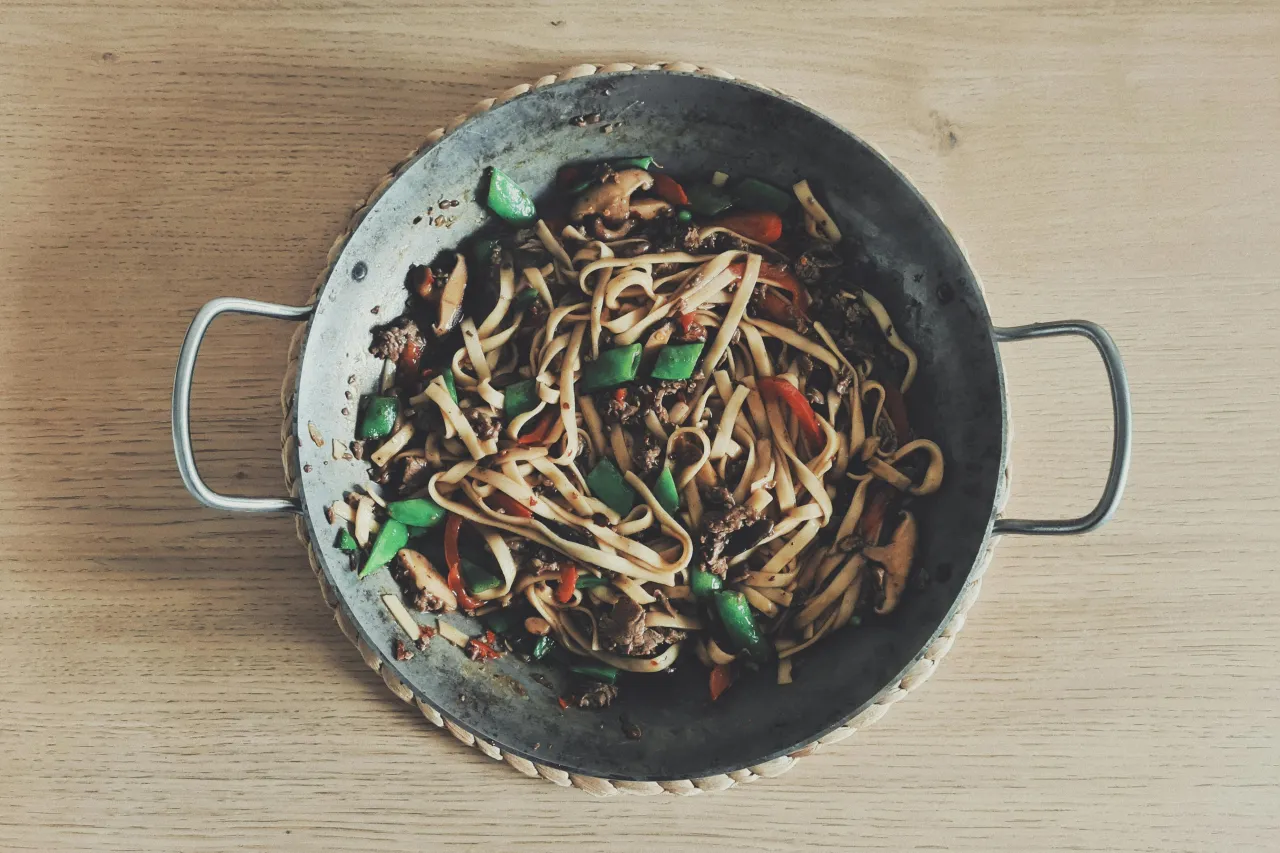 Udon z wołowiną przepis: sycące danie z makaronem udon, kawałkami wołowiny, zieloną papryką i grzybami w sosie, podane w metalowej woku.