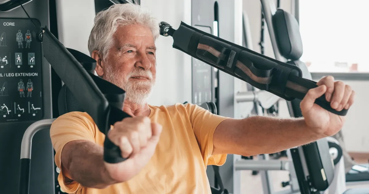 Starsza osoba trenująca siłowo z uśmiechem