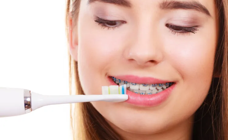 osoba myjąca zęby szczoteczką soniczną z aparatem ortodontycznym