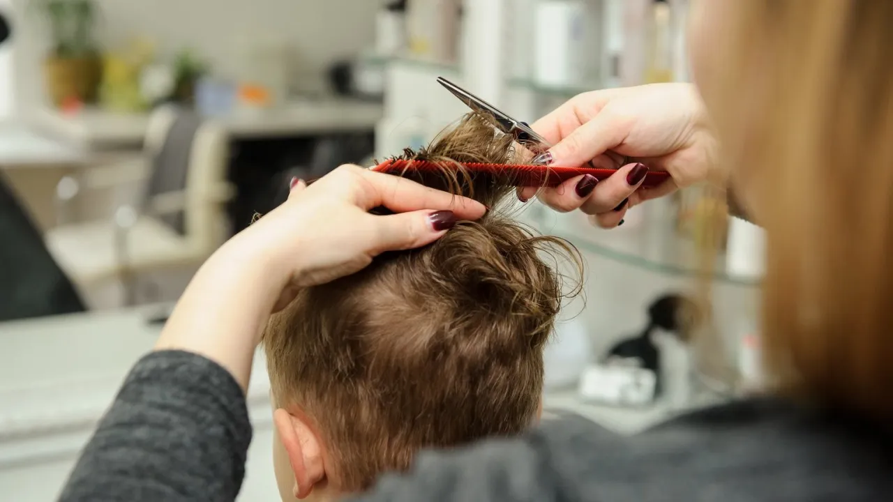 Fryzjerka obcina włosy dziecku. Czy obcinanie włosów dziecku wzmacnia je? To pytanie nurtuje wielu rodziców.