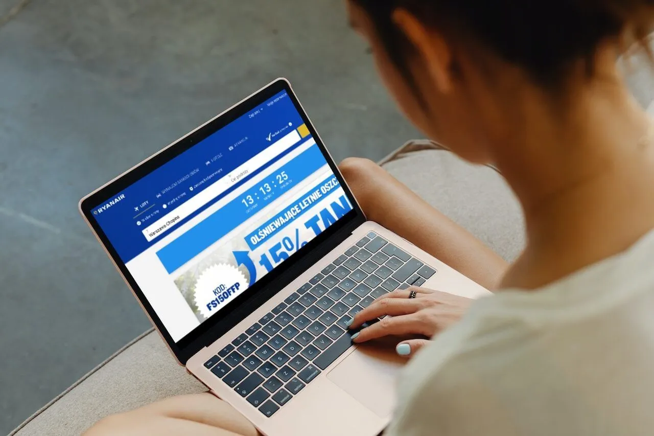 Kobieta szuka tanich lot&oacute;w na stronie Ryanair. Sprawdza, co to jest opłata transakcyjna Ryanair, by zaoszczędzić na wakacjach.