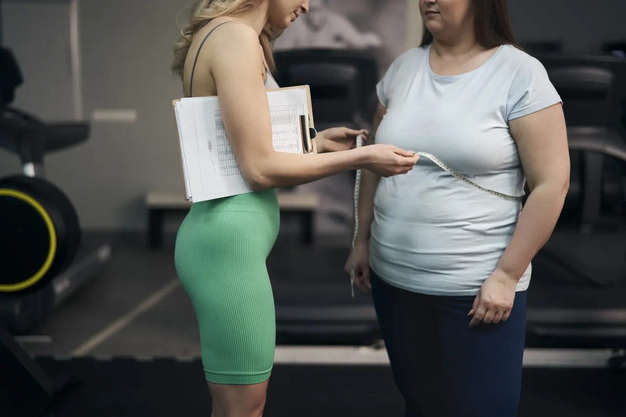 kobieta mierząca obw&oacute;d talii centymetrem