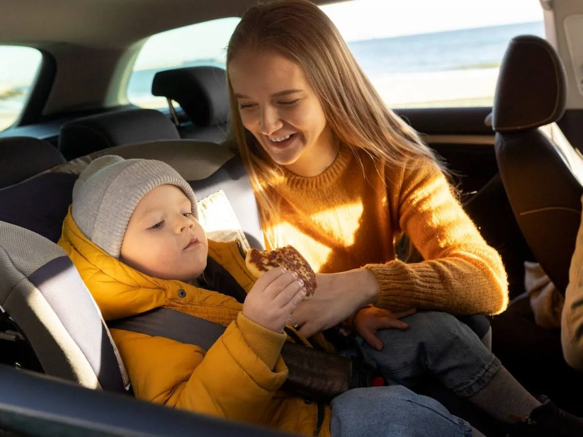 Rodzic zapinający dziecko w foteliku na tylnej kanapie