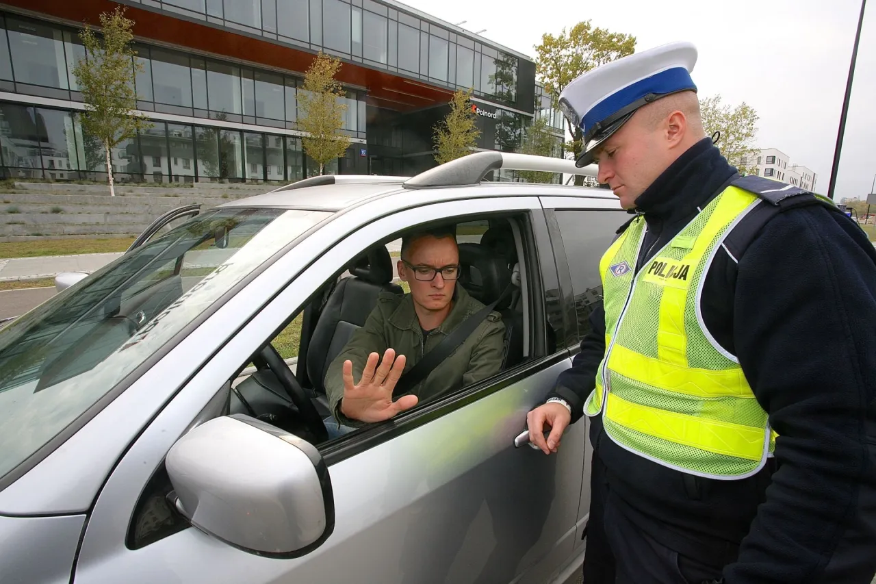Policjant rozmawia z kierowcą, który może dowiedzieć się, na ile zabierają prawo jazdy za prędkość.