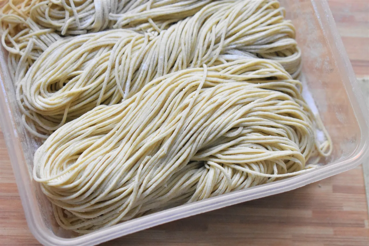 Surowe, cienkie nitki makaronu w pojemniku. Idealne, by dowiedzieć się, jaki makaron do ramen wybrać.