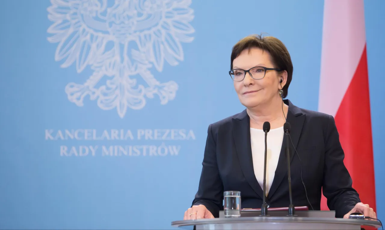 Kobieta w okularach, w garniturze, przemawia na tle godła Polski. To ona, wraz z rządem, kształtowała Polskę, kto rządził w latach 2007-2015.