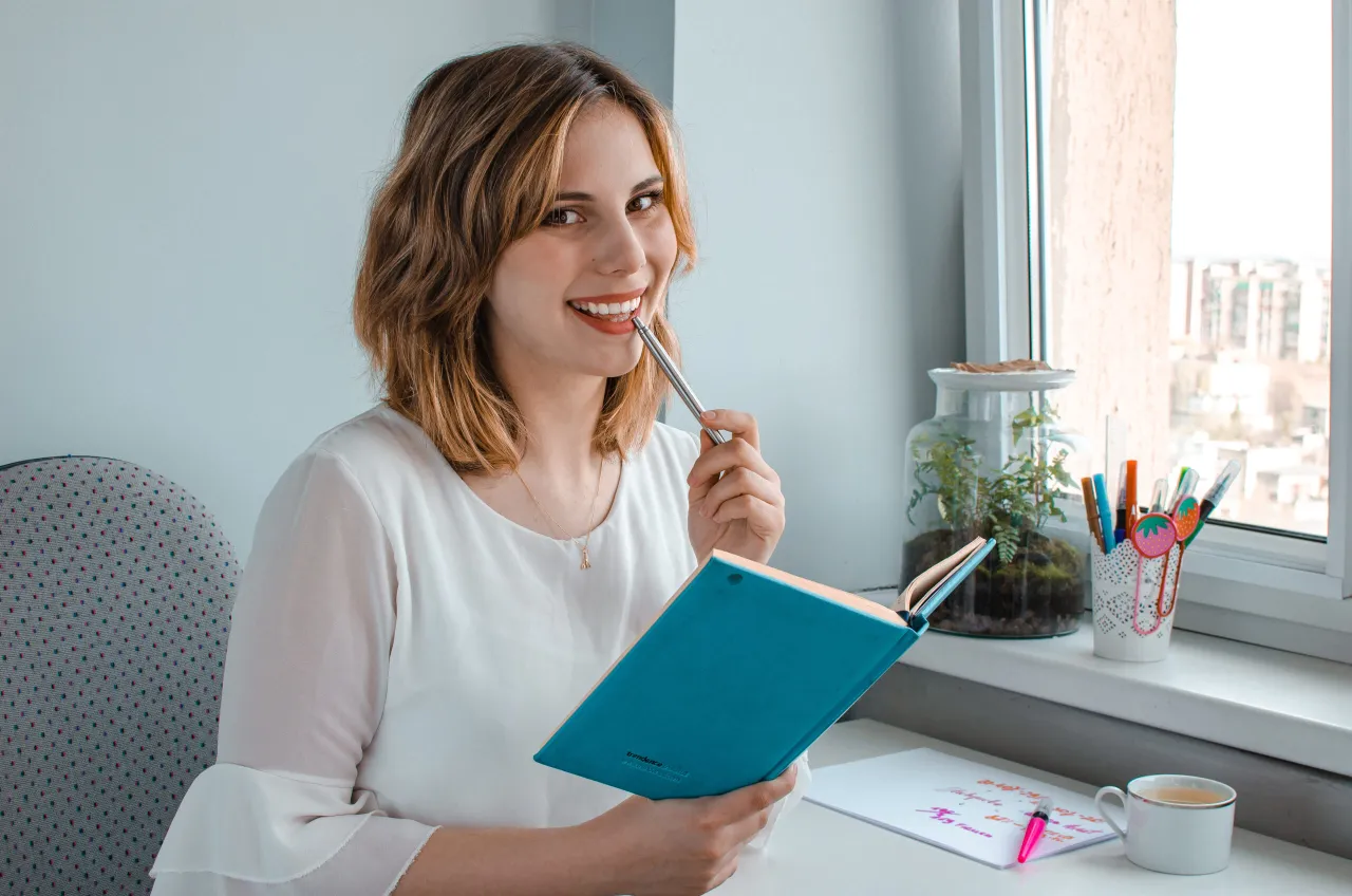 Osoba czytająca książkę z notatkami i zakreślaczami