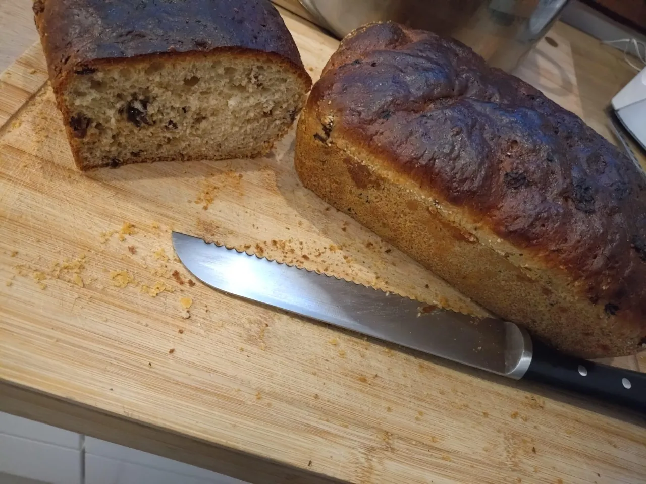 Dwa bochenki chleba na desce, jeden przekrojony. Czy pies może jeść chleb? N&oacute;ż czeka na kromkę.