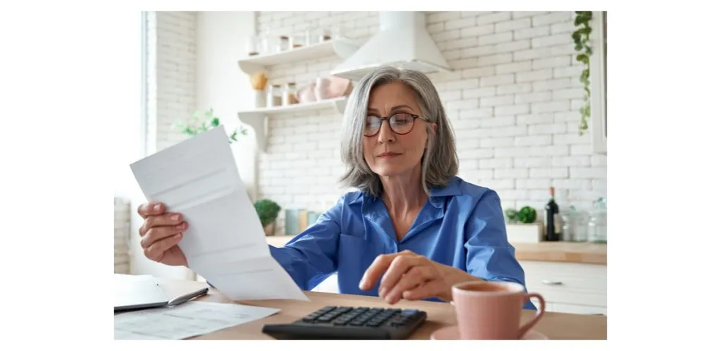 starsza osoba analizująca dokumenty finansowe w domu