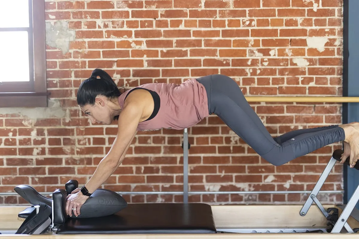 Kobieta ćwiczy na reformerze pilates. Czy to joga czy pilates, co lepsze na kręgosłup?