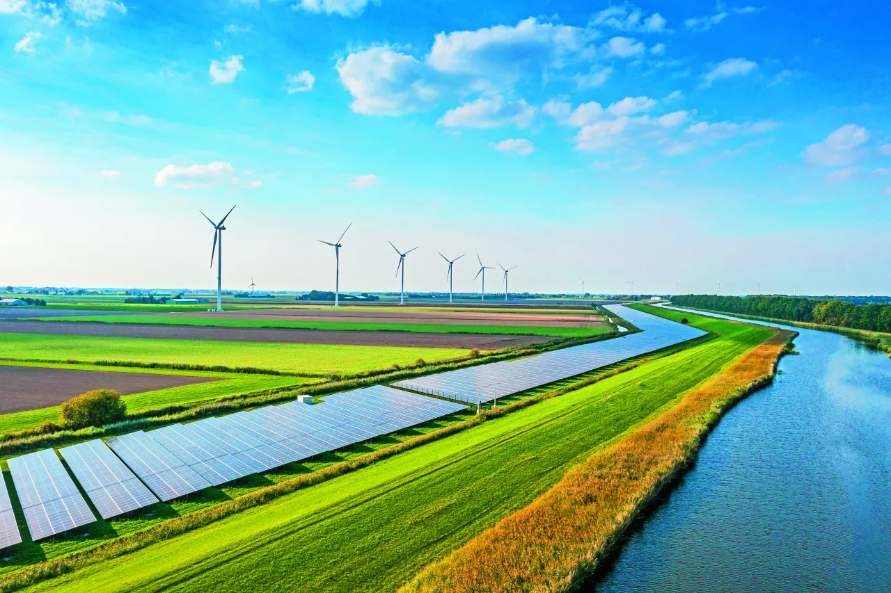 Wiatraki i panele słoneczne na tle p&oacute;l i rzeki. To przyszłość polskich źr&oacute;deł energii elektrycznej.