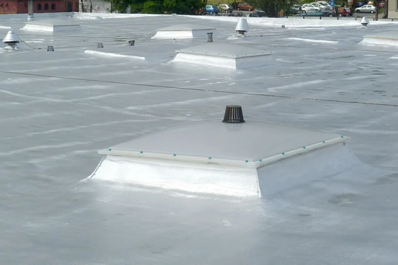 Nowoczesne ocieplenie dachu płaskiego od zewnątrz z widocznymi świetlikami dachowymi i elementami wentylacyjnymi.