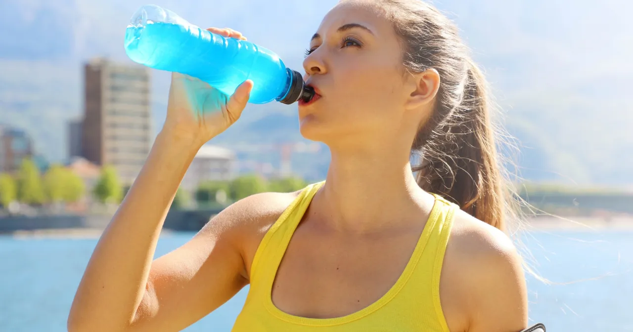 Sportowiec pije nap&oacute;j izotoniczny, osoba starsza pije wodę