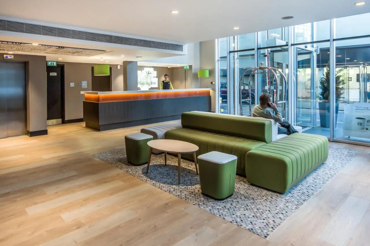 Nowoczesne lobby hotelowe z recepcją i wygodną strefą wypoczynkową. Idealne miejsce, by sprawdzić, gdzie najlepiej nocować w Londynie.