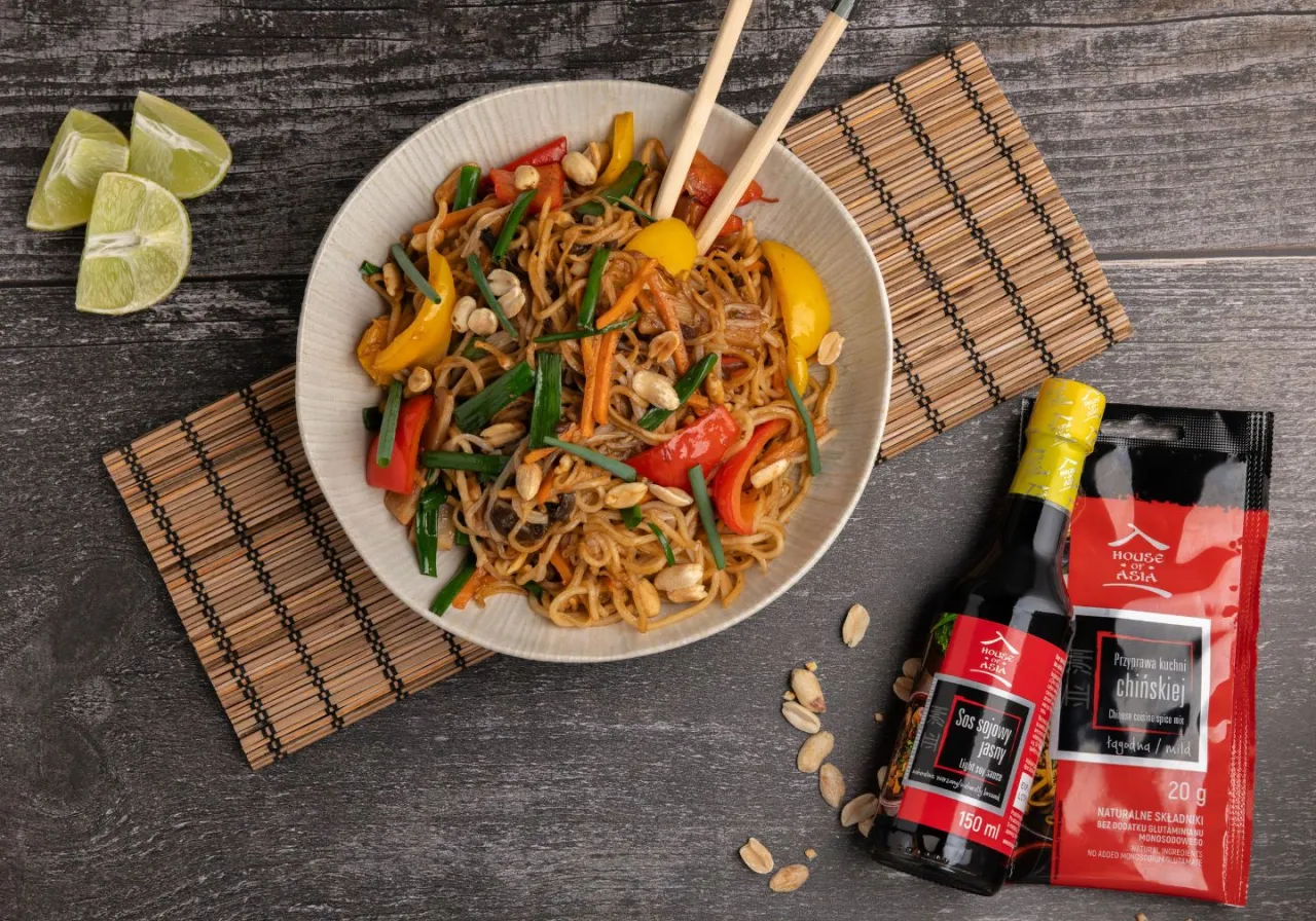 Pyszny makaron sojowy z kurczakiem jak od chińczyka, z warzywami i orzeszkami, podany z limonką i sosem sojowym.