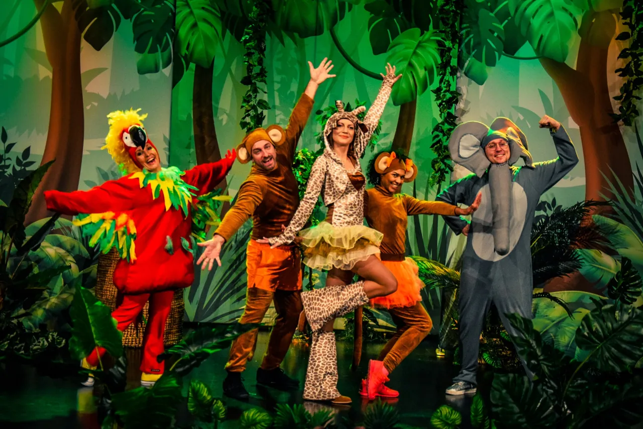 Zuzanna w stroju żyrafy na wesołym spektaklu w dżungli. Wesołe zwierzątka na scenie.