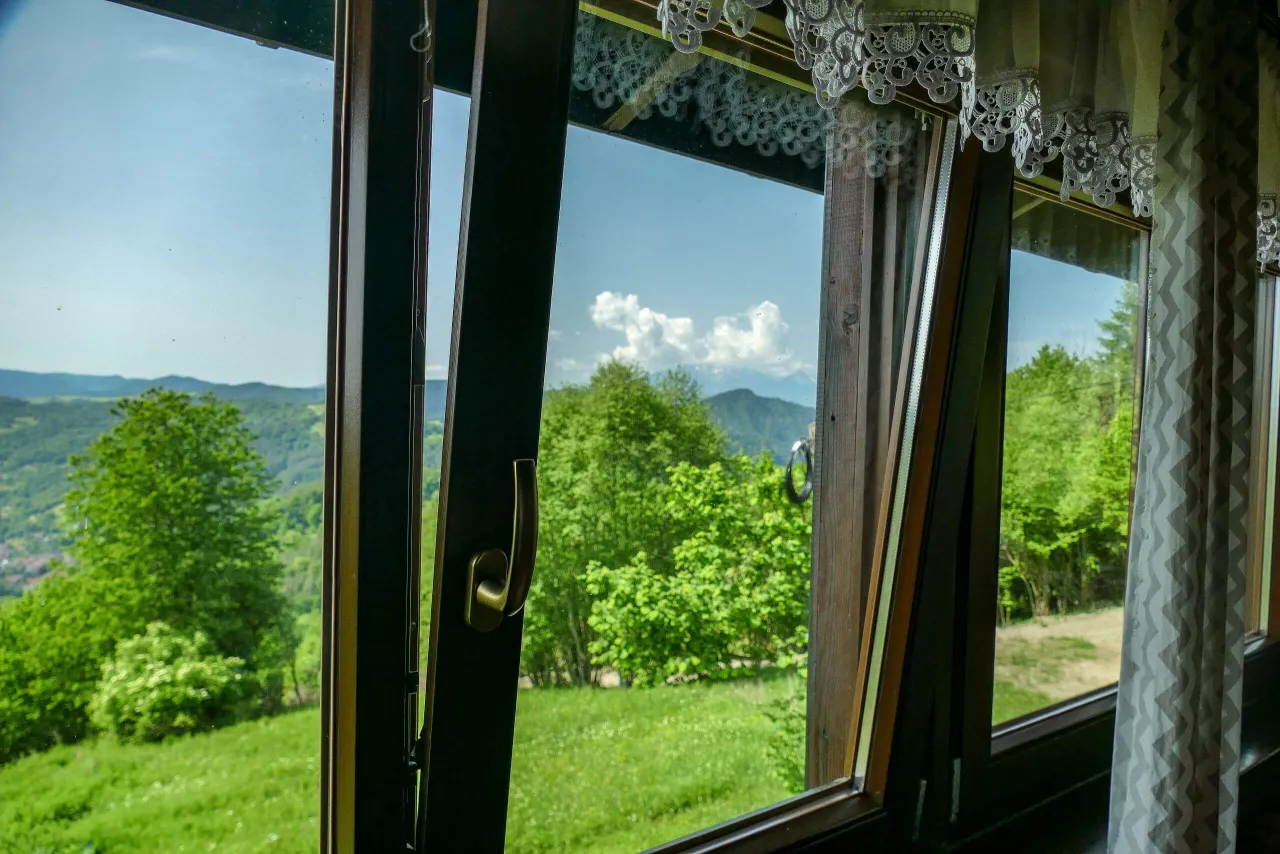 Widok z okna na zielone wzg&oacute;rza i lasy. W oddali majaczą g&oacute;ry. To idealne miejsce na wypoczynek w bac&oacute;wce pod Bereśnikiem.