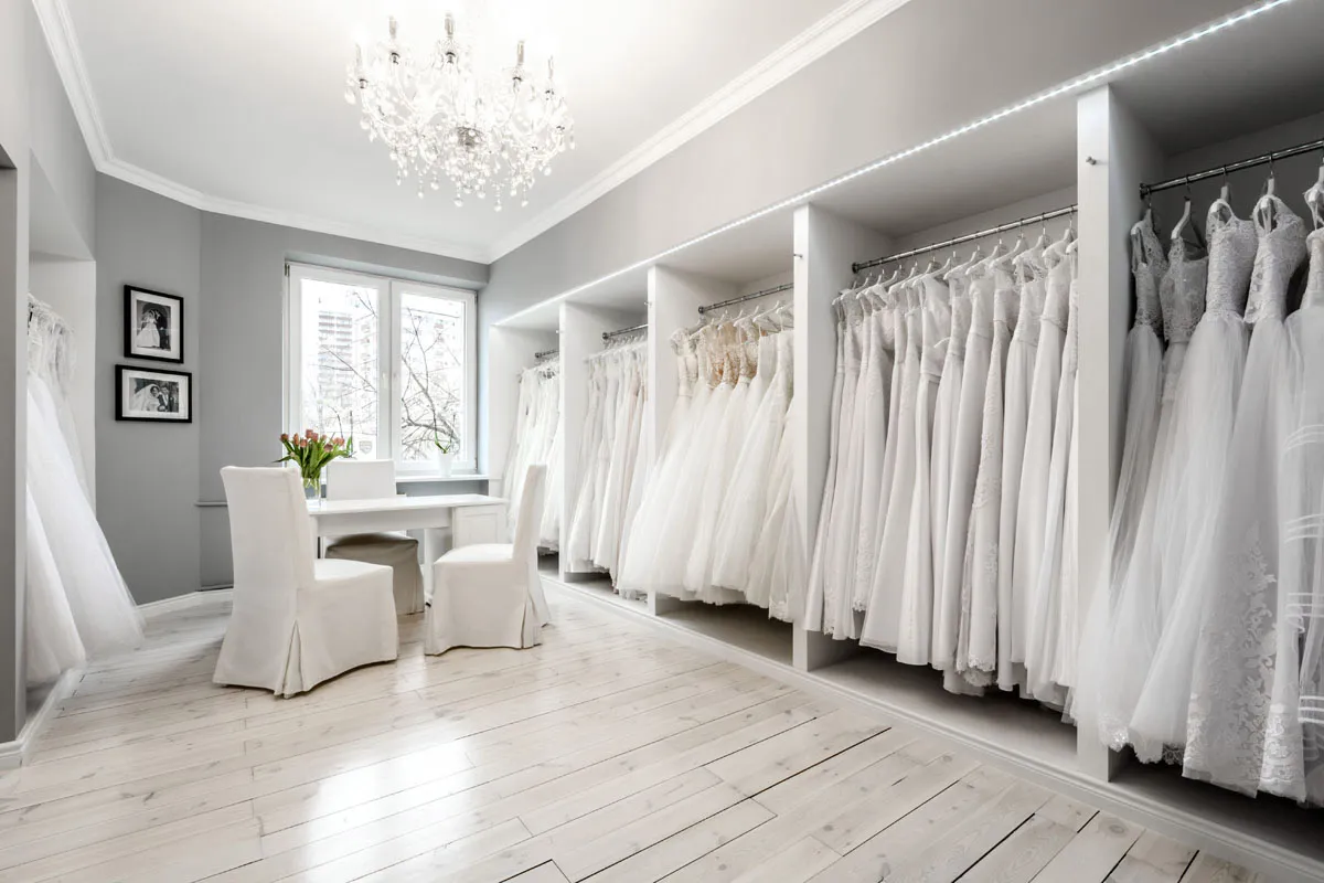 Kobieta przeglądająca oferty sukien ślubnych na laptopie, obok smartfon z aplikacją