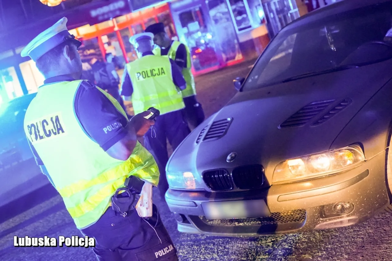 Policjanci w kamizelkach odblaskowych zatrzymali kierowcę podejrzanego o nielegalne wyścigi. Na drodze panuje nocny ruch.