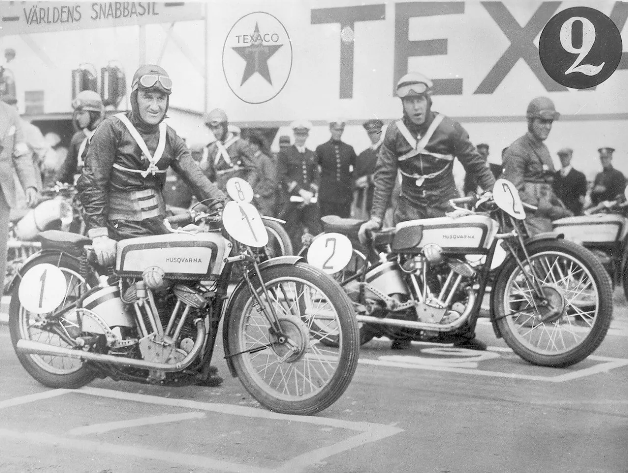 Zawodnicy Husqvarna Motorcycle Company na motocyklach z numerami 1 i 2, gotowi do startu wyścigu.