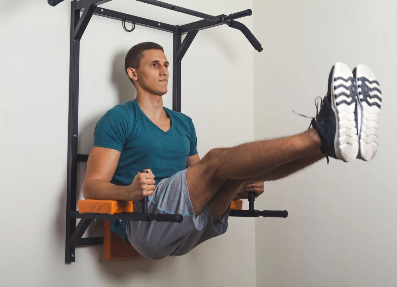 Mężczyzna wykonuje ćwiczenie na brzuch na drążku. To przykład treningu oporowego, kt&oacute;ry buduje siłę.