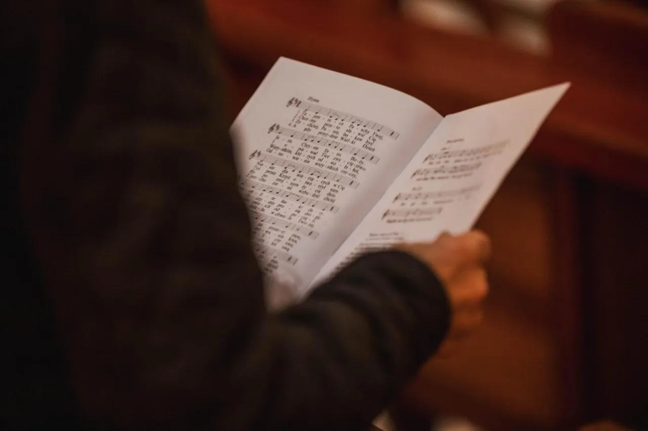 Osoba trzyma nuty z pieśnią 