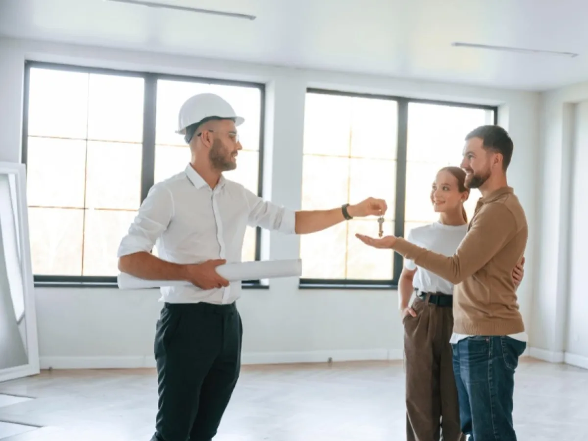 Inżynier przekazuje klucze parze, symbolizując zgłoszenie zakończenia budowy.