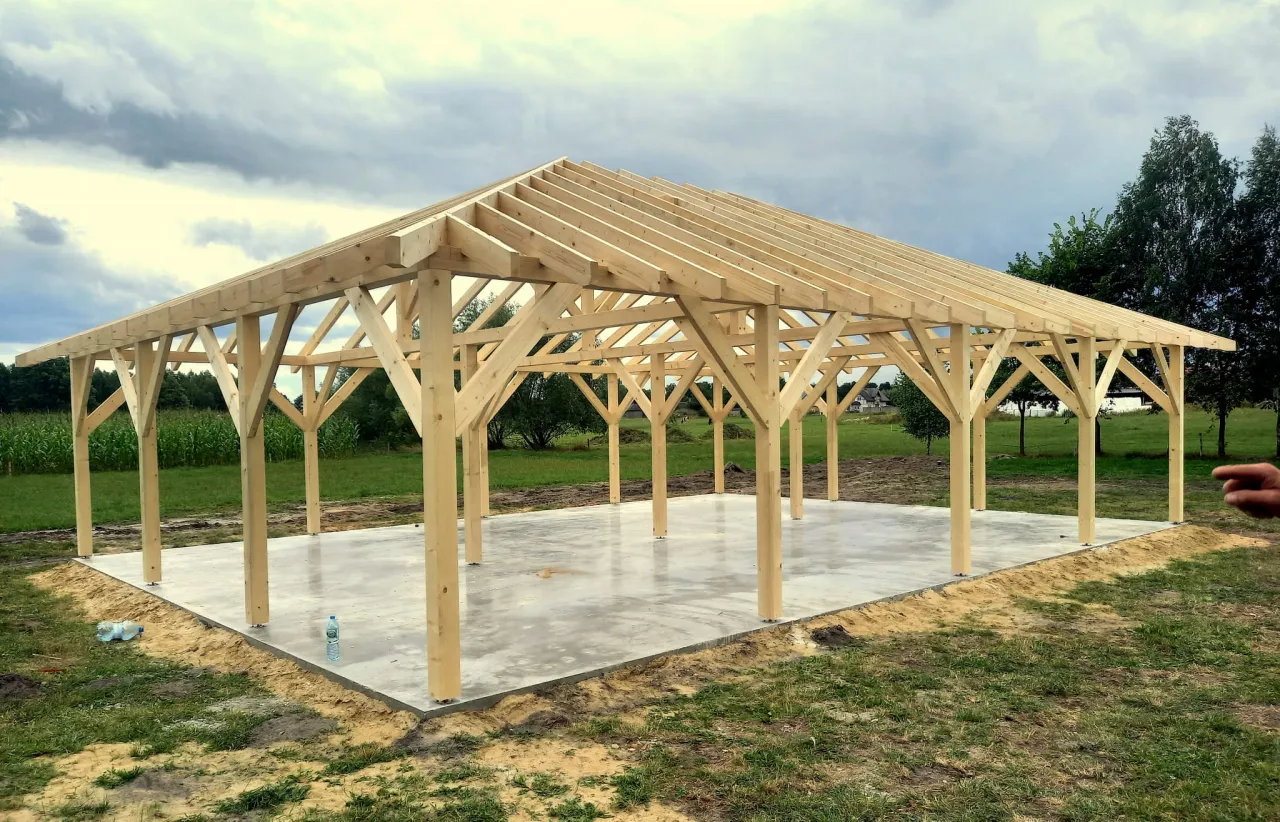 Konstrukcja dachu kopertowego na altanie w budowie. Drewniane krokwie i słupy tworzą szkielet, gotowy na pokrycie.