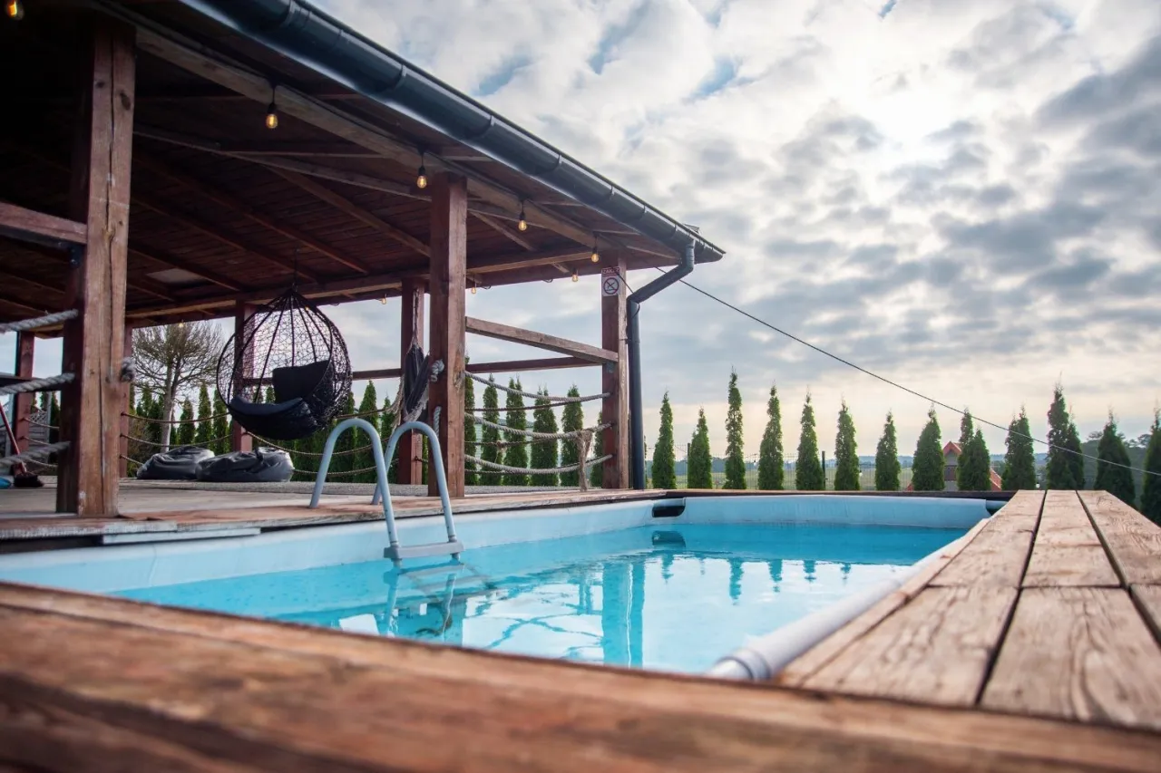 Relaks w domku spa na Mazurach: basen, huśtawka i widok na cyprysy. Idealne miejsce na odpoczynek.